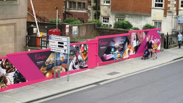 Custom printed hoarding panels installed around a construction site with company advertising and branding for the new hotel that is being developed