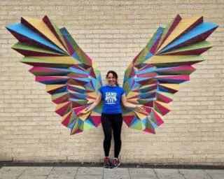 Photo of angel wings made out of wall stickers with a lady stood in the middle to complete the image
