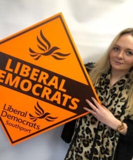woman holding a day glo printed election campaign board