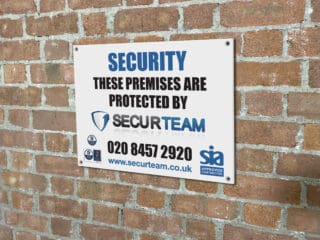 custom printed security sign board displayed on brick