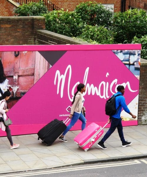 people walking by Malmaison hoarding board