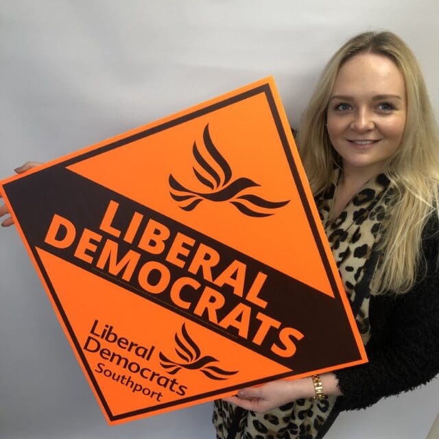 lady holding Liberal Democrat election marketing signs