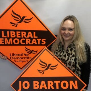 woman holding Liberal Democrat campaign boards
